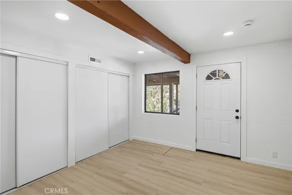 a view of an empty room with wooden floor and a window