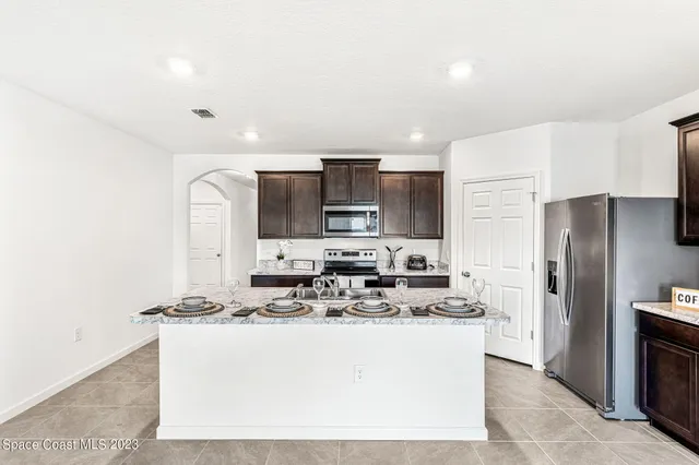 a kitchen with kitchen island stainless steel appliances a refrigerator stove a sink and a oven