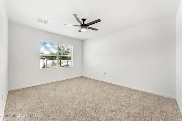an empty room with a window and a fan