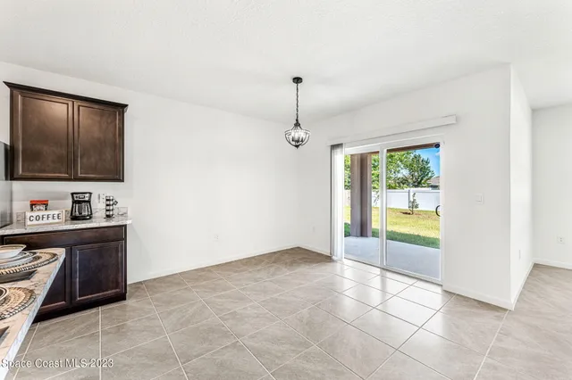 a view of an empty room with a window and kitchen view