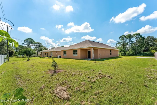 a backyard of a house with table and chairs plants and large tree
