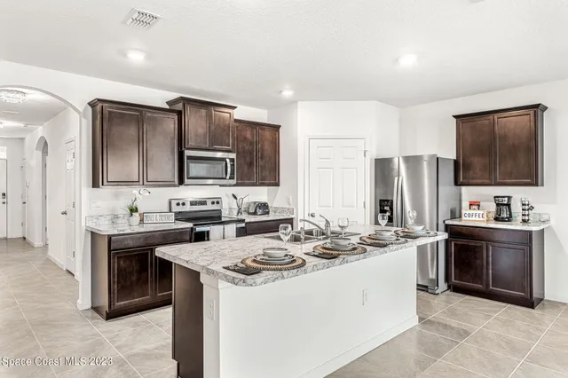 a kitchen with stainless steel appliances kitchen island granite countertop a sink stove and refrigerator