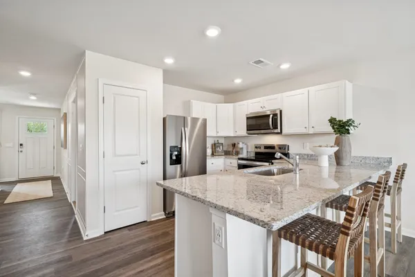a kitchen with stainless steel appliances granite countertop a refrigerator a stove a microwave a sink and dishwasher with wooden floor