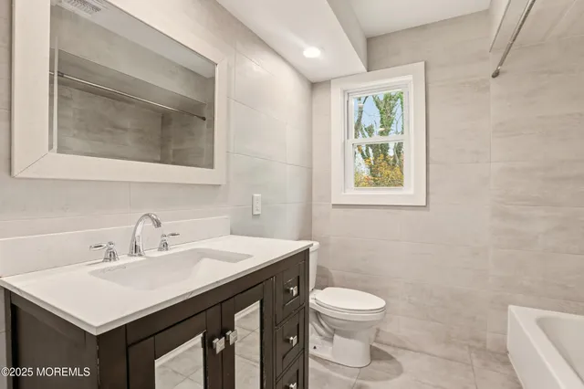 a bathroom with a toilet a sink a mirror and a window