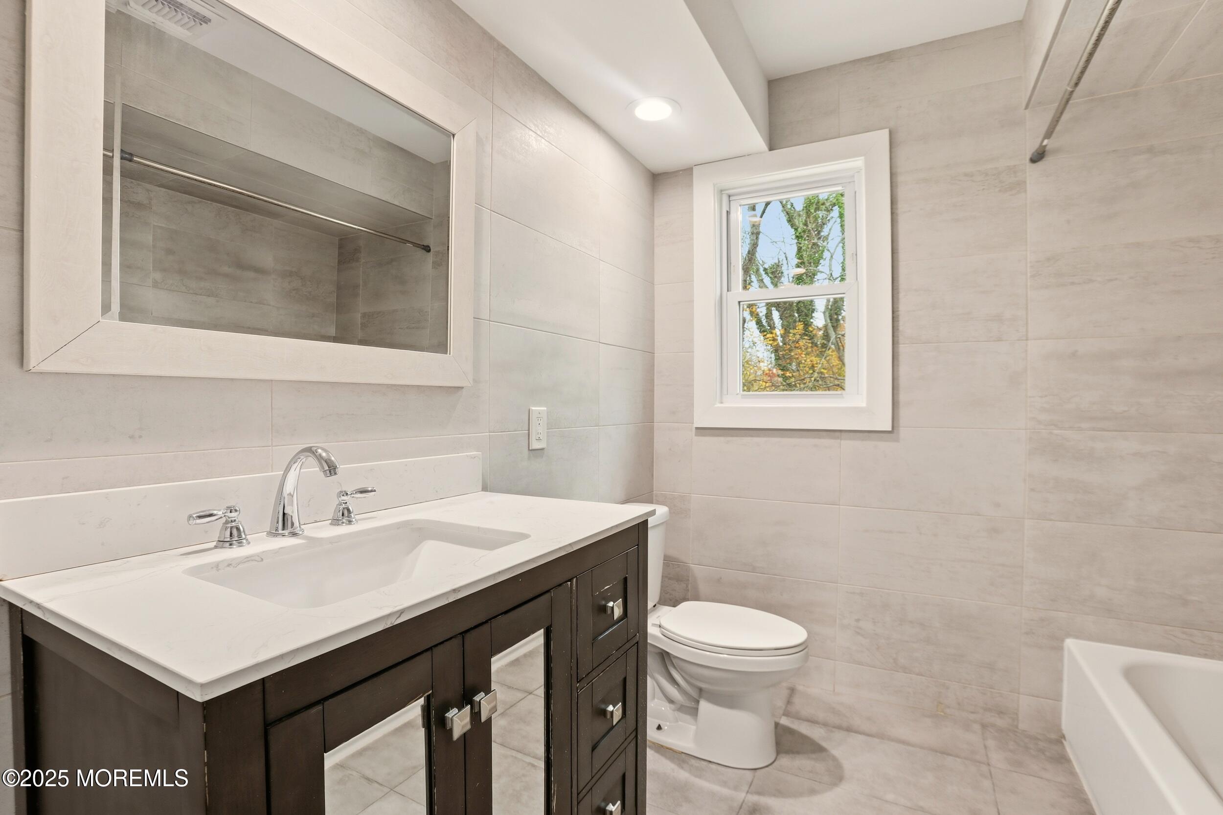 2930 Highway 9 Howell, NJ 07731 - Photo 20 of 30 a bathroom with a toilet a sink a mirror and a window