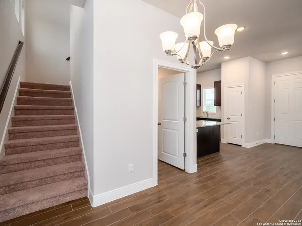 a view of a hallway with wooden floor and chandelier