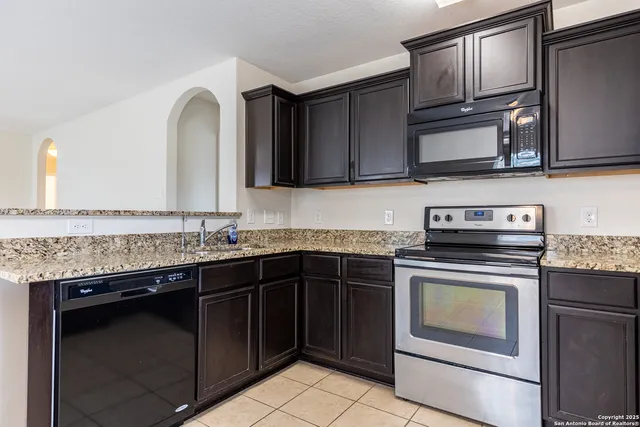 a kitchen with granite countertop a stove top oven microwave and cabinets