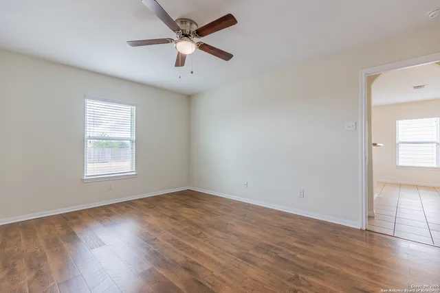 an empty room with wooden floor and windows