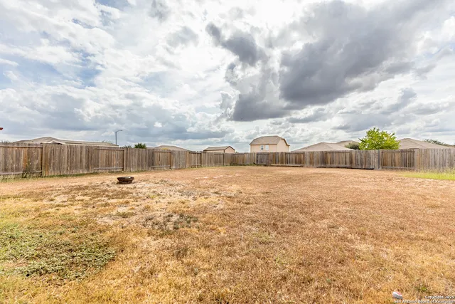 a view of a dry yard with wooden fence