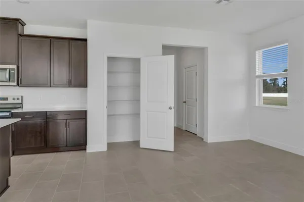 a view of an empty room with kitchen and a window