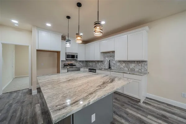 a large kitchen with granite countertop a stove oven and a refrigerator