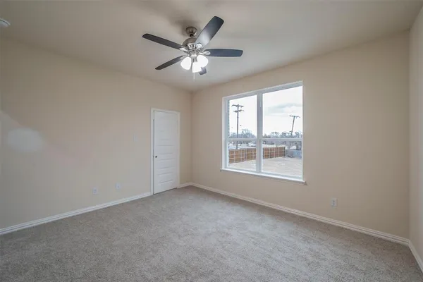 an empty room with chandelier fan and windows