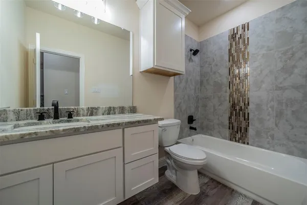 a bathroom with a granite countertop toilet a sink and a bathtub