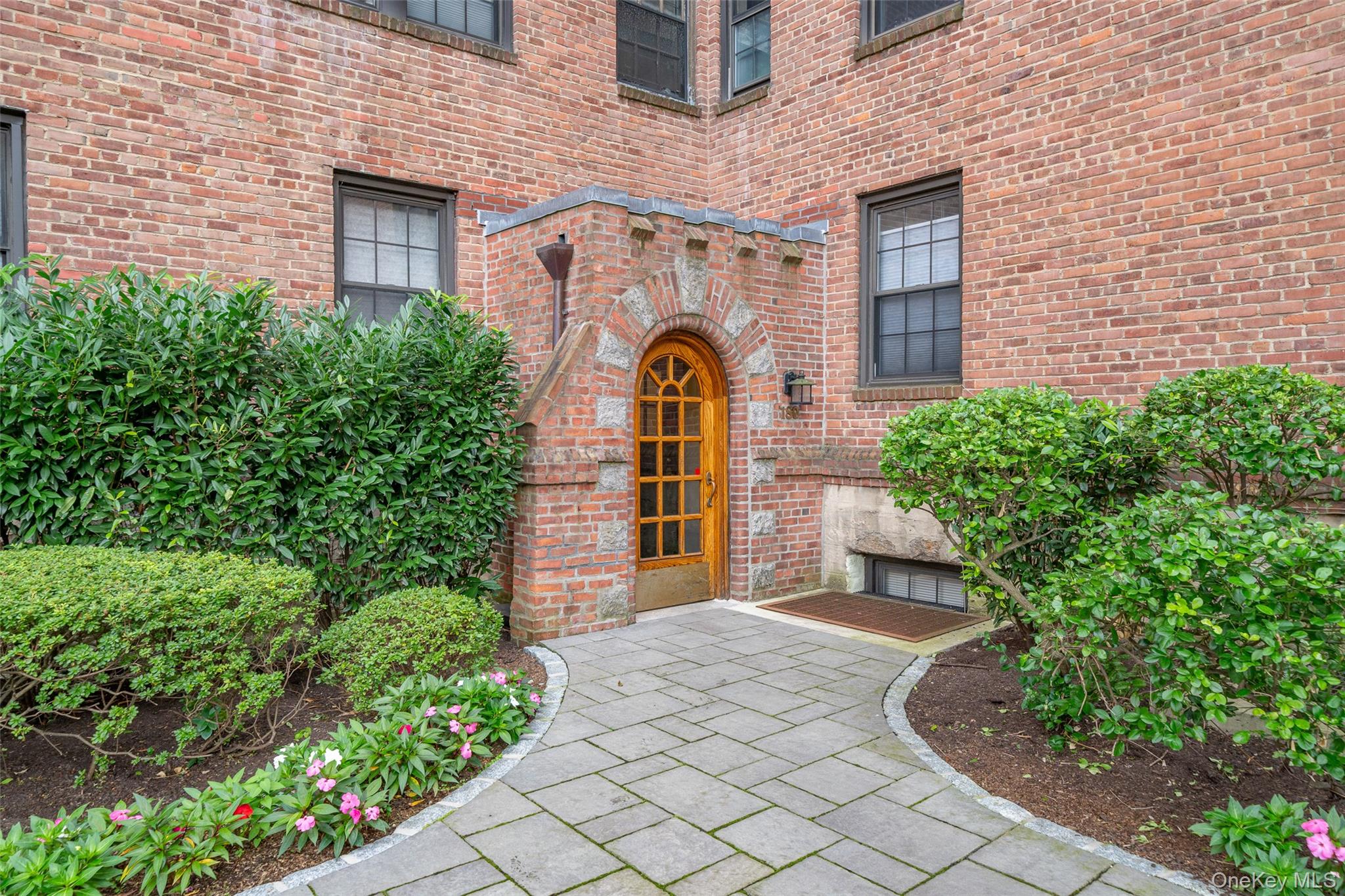 180 Garth Road, Unit 5F Scarsdale, NY 10583 - Photo 17 of 26 a front view of a house with a garden