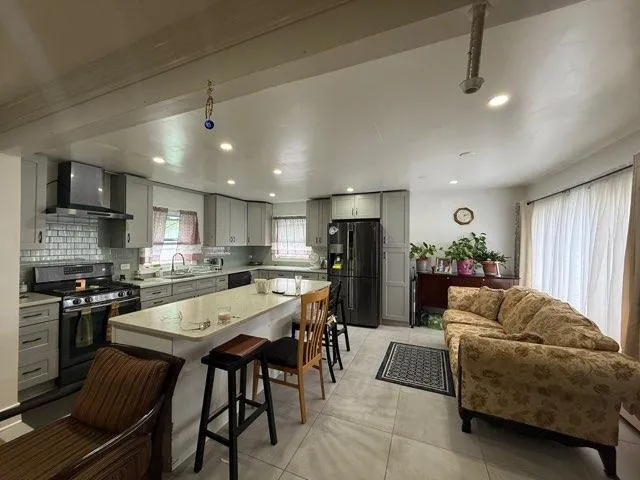 a living room with stainless steel appliances furniture a dining table and kitchen view