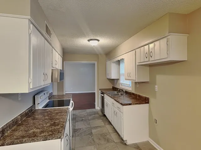 a kitchen with granite countertop a sink a stove and cabinets