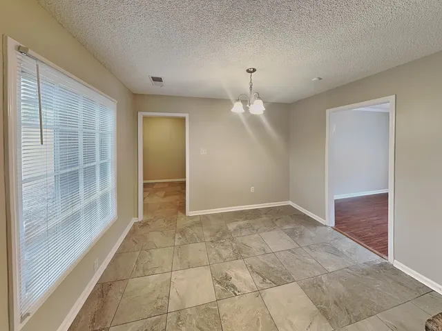 a view of empty room with wooden floor fan and window