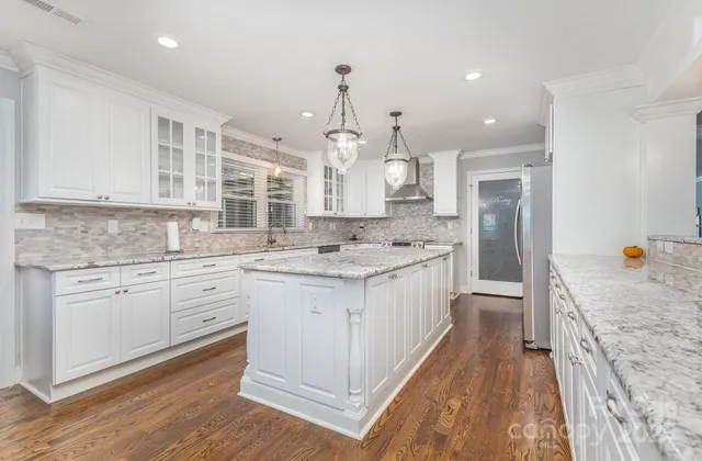 a kitchen with granite countertop a sink stove refrigerator and cabinets