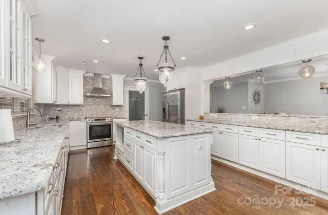 a large kitchen with granite countertop a stove top oven a sink a counter space and cabinets