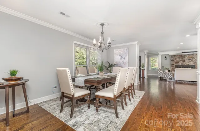 a dining room with wooden floor a chandelier a wooden table and chairs