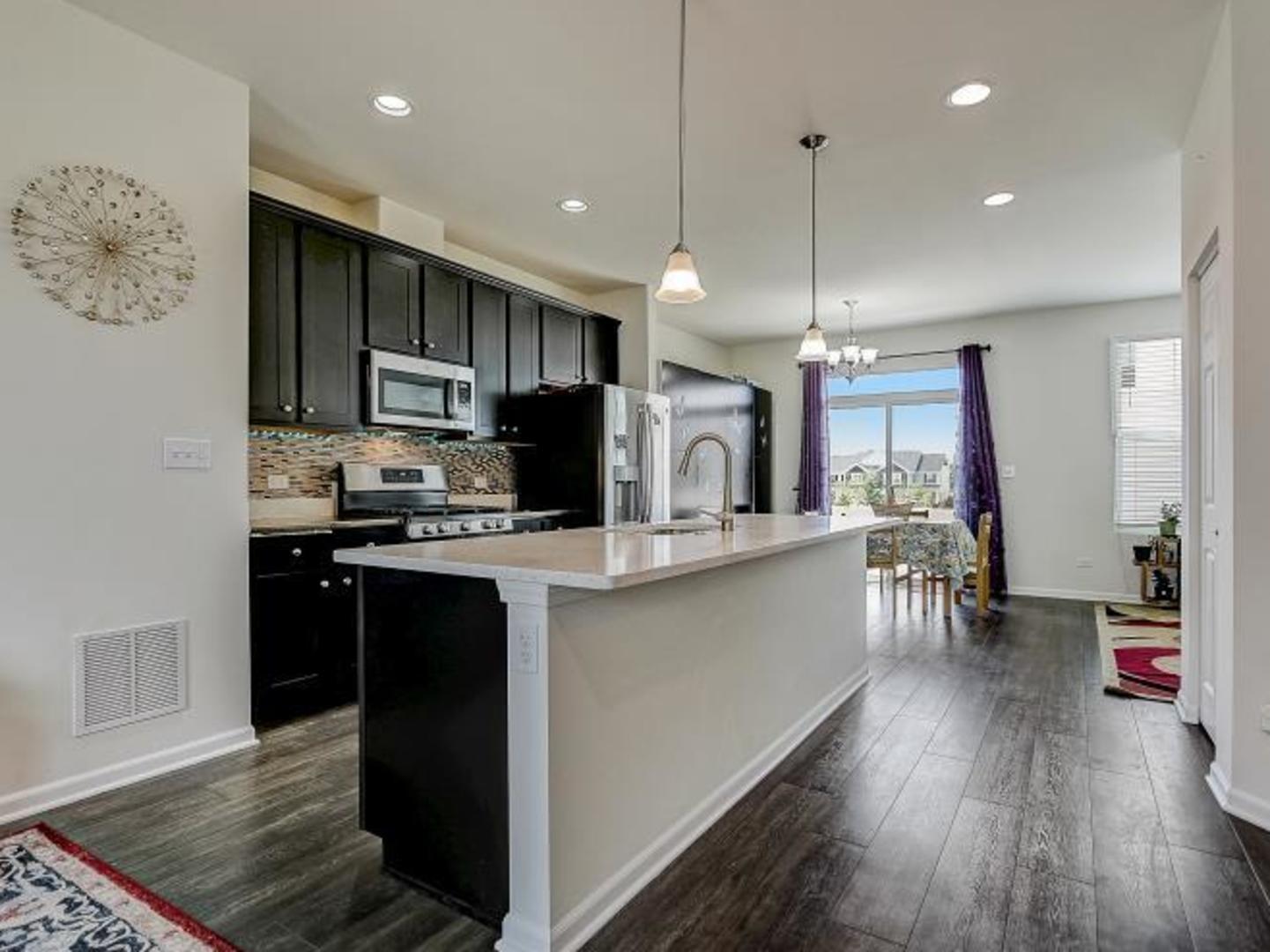 4156 Irving Road Aurora, IL 60504 - Photo 3 of 28 a kitchen with stainless steel appliances kitchen island granite countertop a refrigerator a sink dishwasher a stove and a microwave with wooden floor