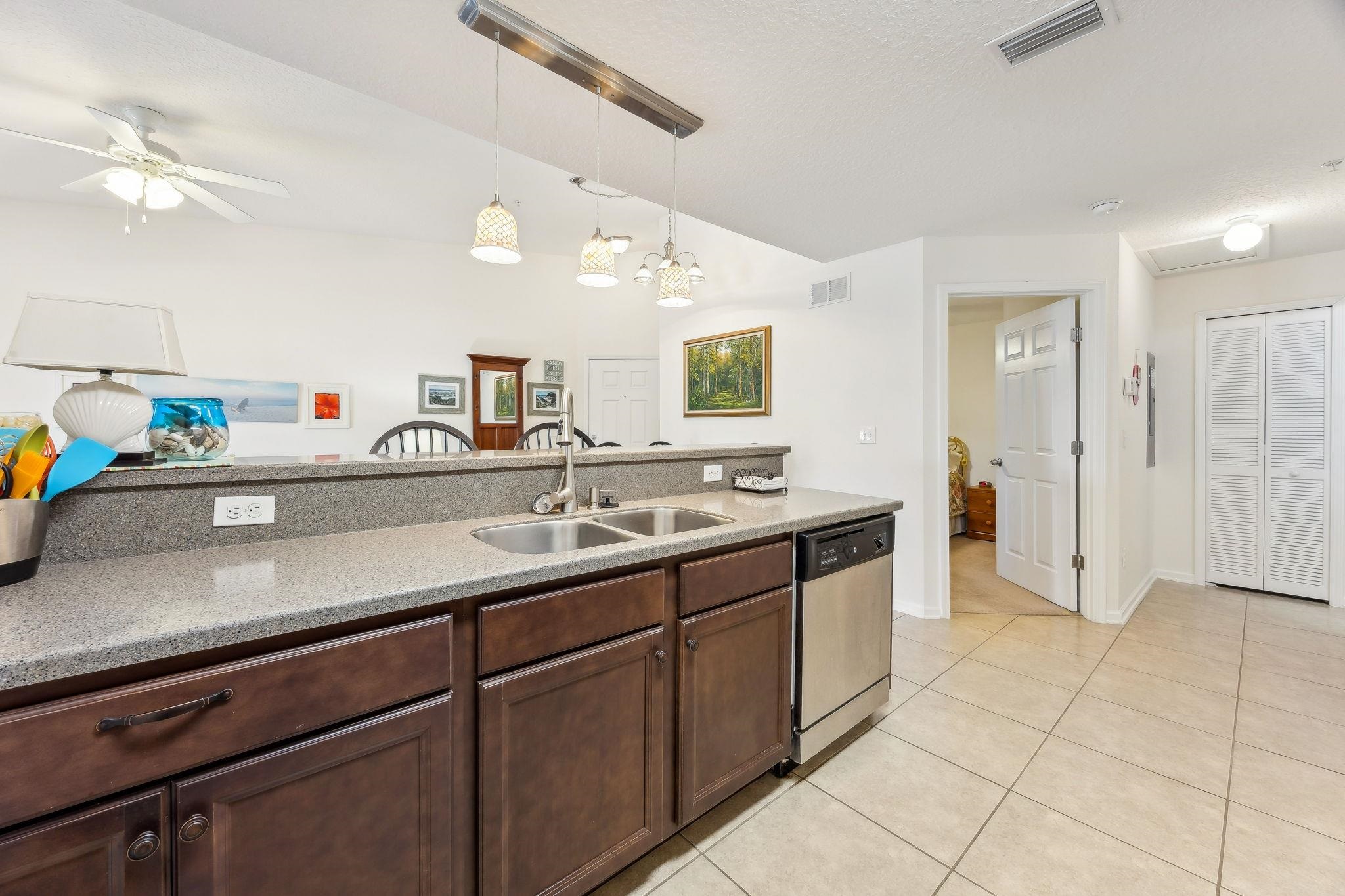 2861 Golden Lake Loop St. Augustine, FL 32084 - Photo 10 of 40 Kitchen featuring decorative light fixtures, stainless steel dishwasher, light stone counters, dark brown cabinetry, and light tile patterned floors