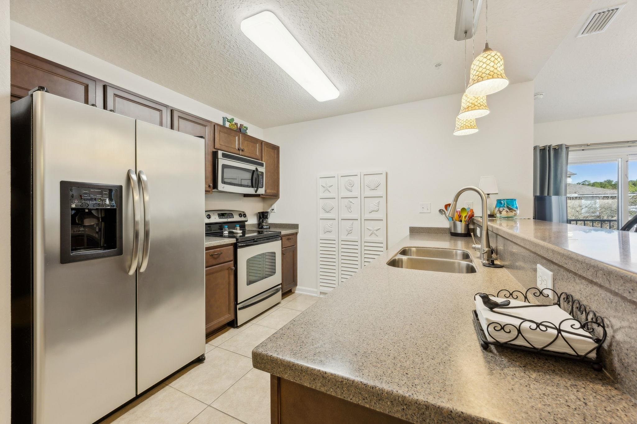 2861 Golden Lake Loop St. Augustine, FL 32084 - Photo 11 of 40 Kitchen with appliances with stainless steel finishes, pendant lighting, a textured ceiling, light tile patterned flooring, and light stone countertops