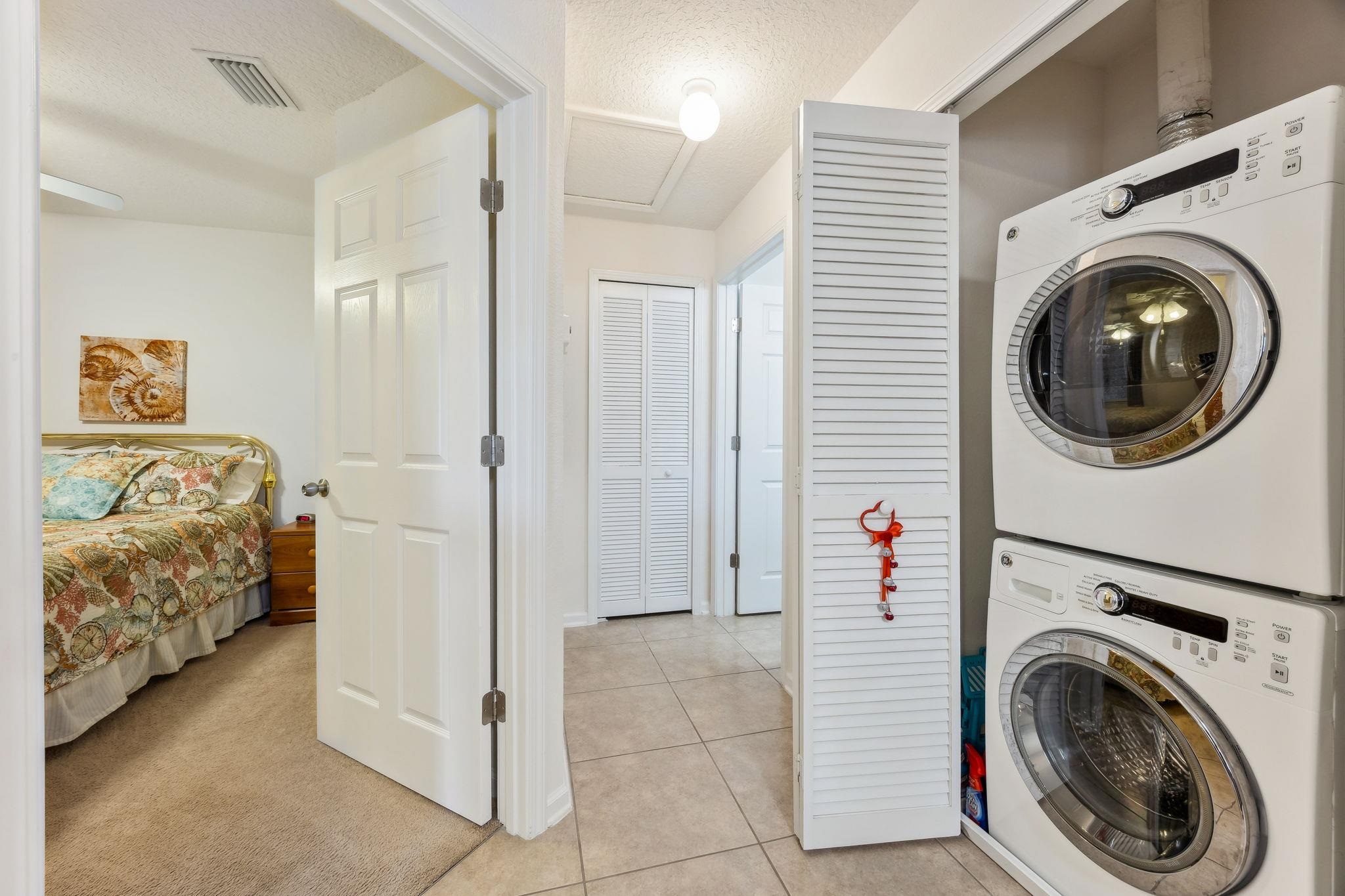 2861 Golden Lake Loop St. Augustine, FL 32084 - Photo 24 of 40 Washroom with stacked washer / drying machine, a textured ceiling, light colored carpet, attic access, and light tile patterned floors