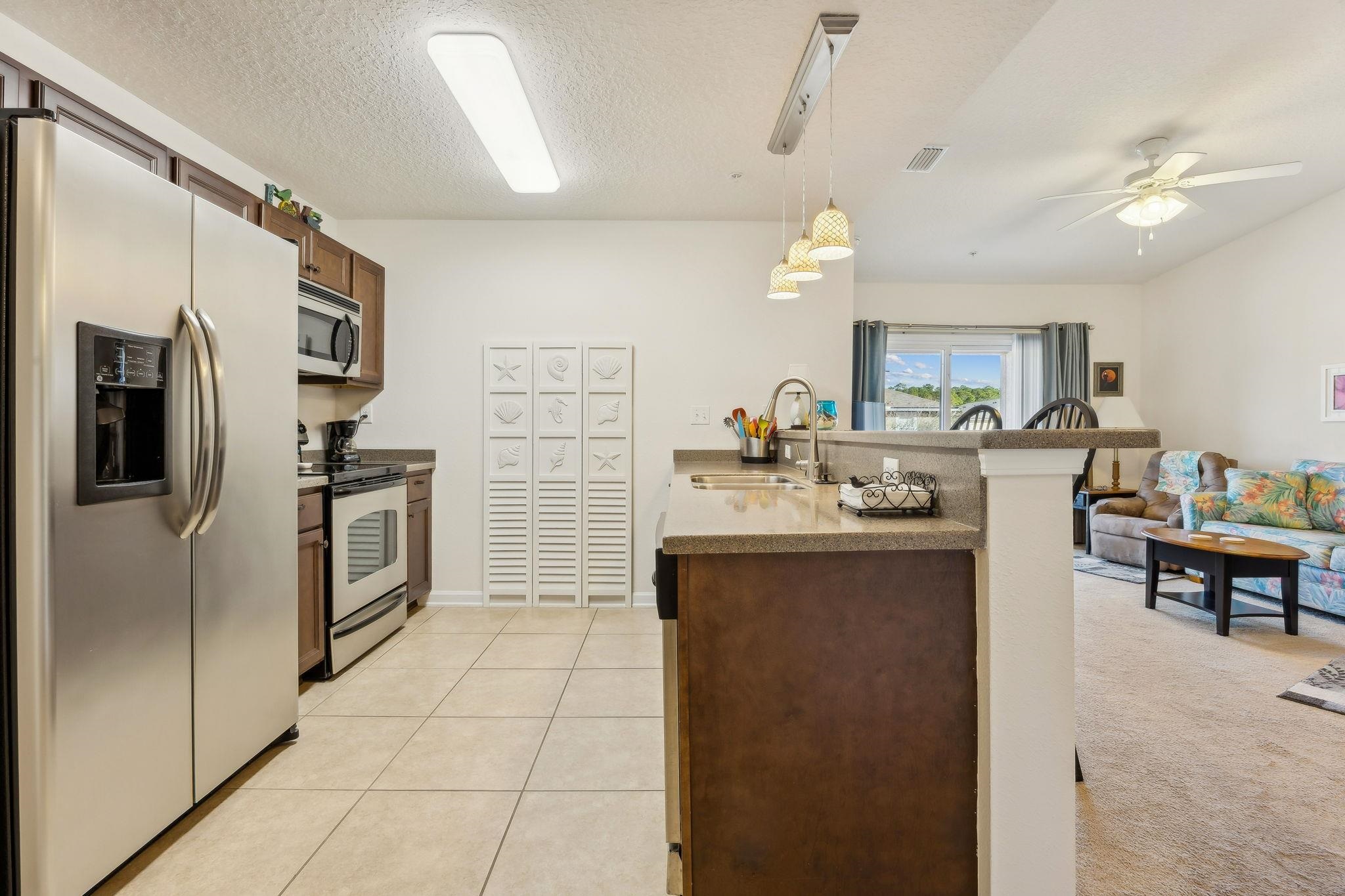 2861 Golden Lake Loop St. Augustine, FL 32084 - Photo 40 of 40 Kitchen featuring appliances with stainless steel finishes, a peninsula, decorative light fixtures, a textured ceiling, and open floor plan