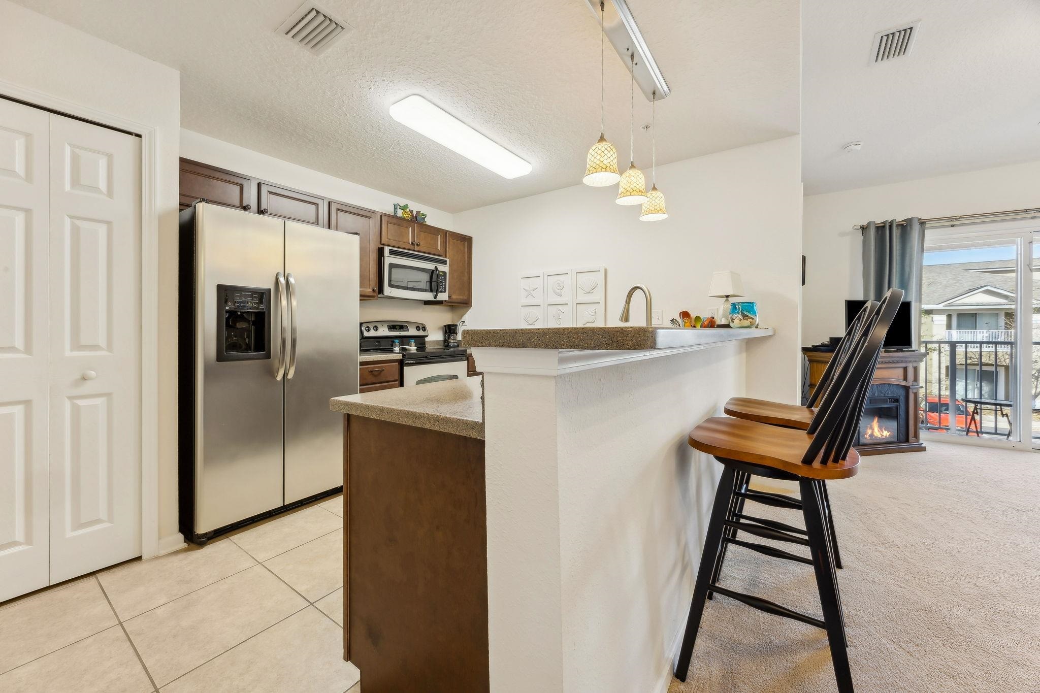 2861 Golden Lake Loop St. Augustine, FL 32084 - Photo 8 of 40 Kitchen featuring a kitchen breakfast bar, stainless steel appliances, a peninsula, pendant lighting, and a textured ceiling