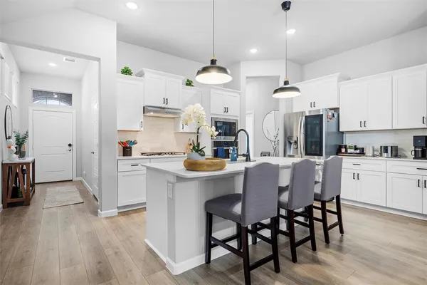 a kitchen with stainless steel appliances kitchen island granite countertop a table chairs and a refrigerator