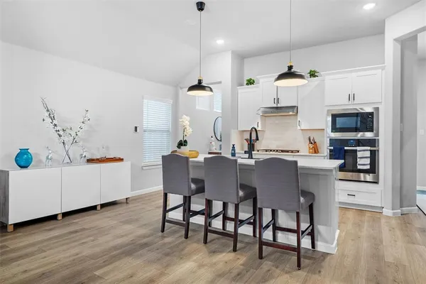 a kitchen with stainless steel appliances kitchen island granite countertop a table chairs and a refrigerator