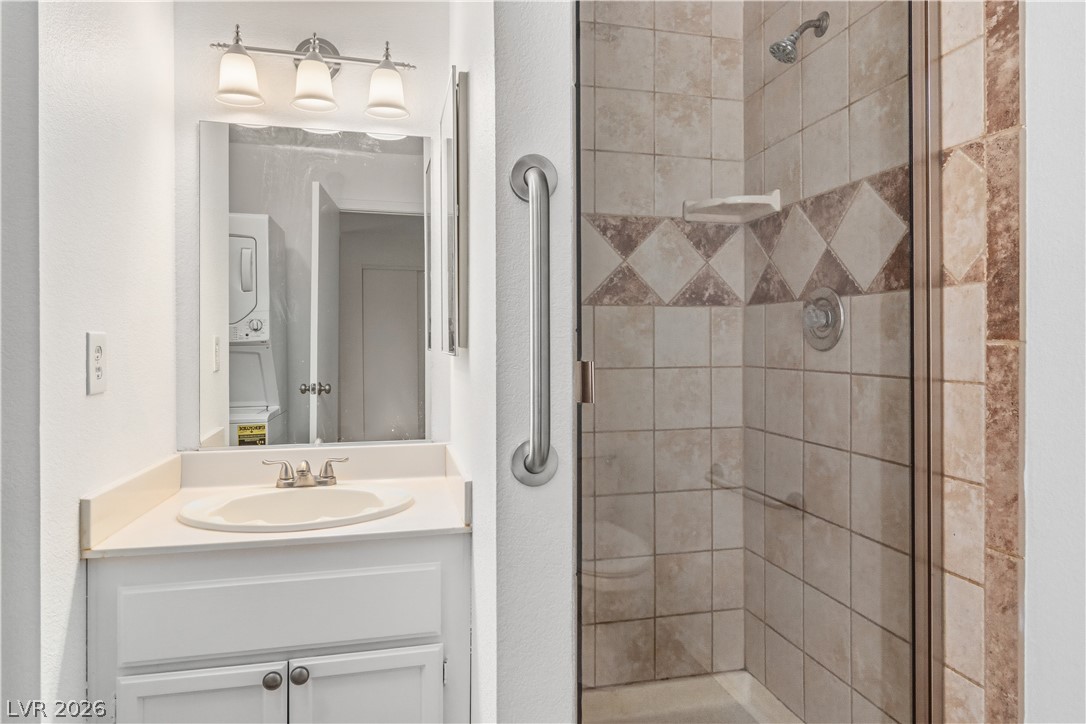 2232 Aspen Mirror Way, Unit 103 Laughlin, NV 89029 - Photo 14 of 50 Full bath featuring a stall shower, vanity, stacked washer / drying machine, and a textured wall