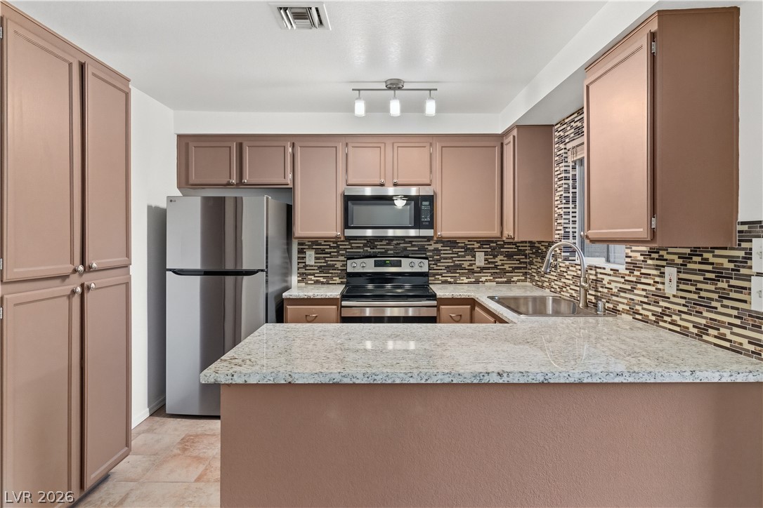 2232 Aspen Mirror Way, Unit 103 Laughlin, NV 89029 - Photo 8 of 50 Kitchen featuring stainless steel appliances, light stone counters, a peninsula, and tasteful backsplash