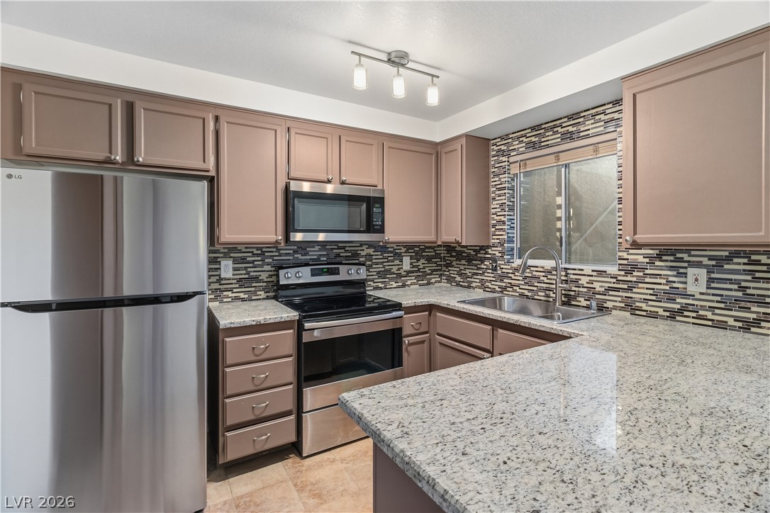 2232 Aspen Mirror Way, Unit 103 Laughlin, NV 89029 - Photo 10 of 50 Kitchen with stainless steel appliances, light stone counters, decorative backsplash, and gray cabinetry