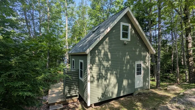 a view of a small house with a small yard plants and large tree