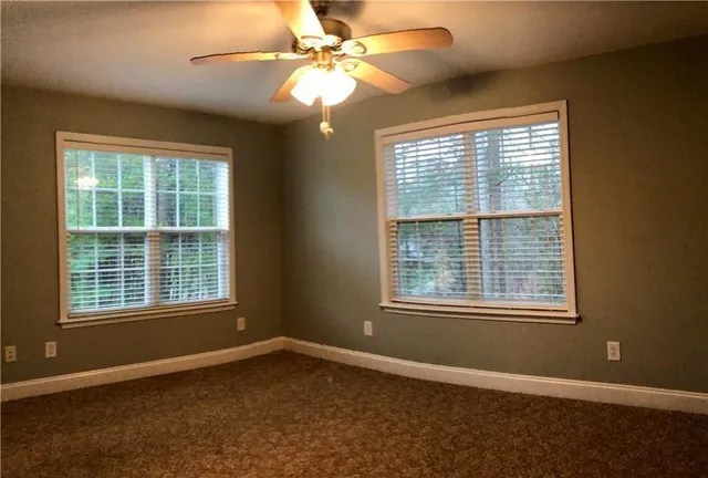 a view of an empty room with a window and a ceiling fan