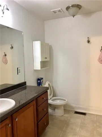 a bathroom with a granite countertop sink a toilet and a mirror