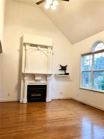 a view of empty room with wooden floor and fireplace