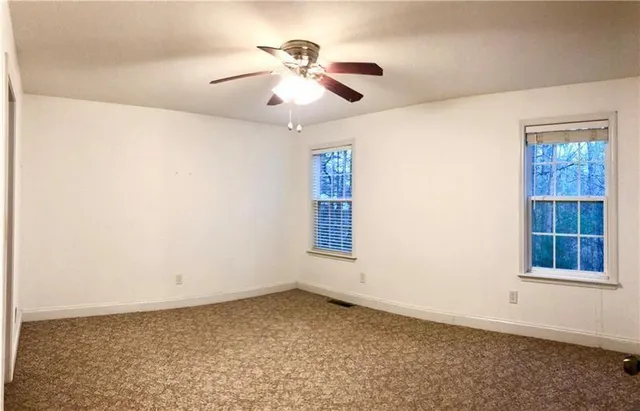 an empty room with windows and chandelier fan