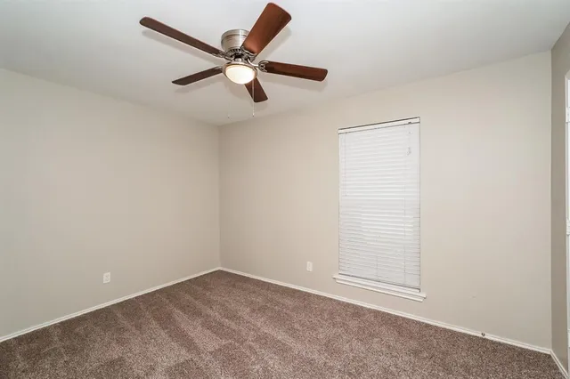 an empty room with a window and a fan