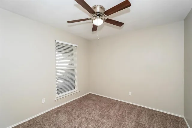 an empty room with a window and a fan