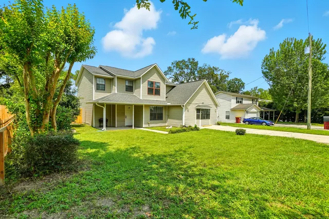 a view of a house with a big yard and large trees
