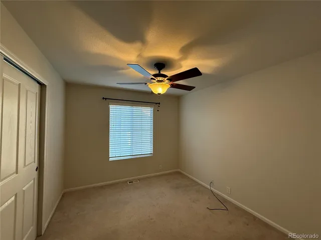 an empty room with a window and a fan