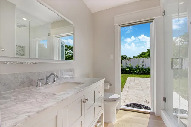 a bathroom with a granite countertop sink mirror vanity and toilet
