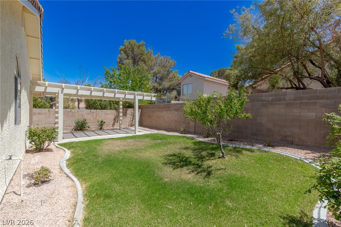 2803 Mirage Road Henderson, NV 89074 - Photo 38 of 39 A private walled backyard features a grassy lawn and a classic white pergola structure.
