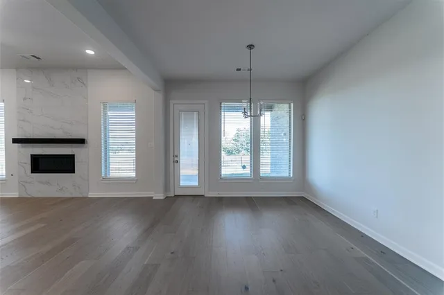 an empty room with wooden floor fireplace and windows