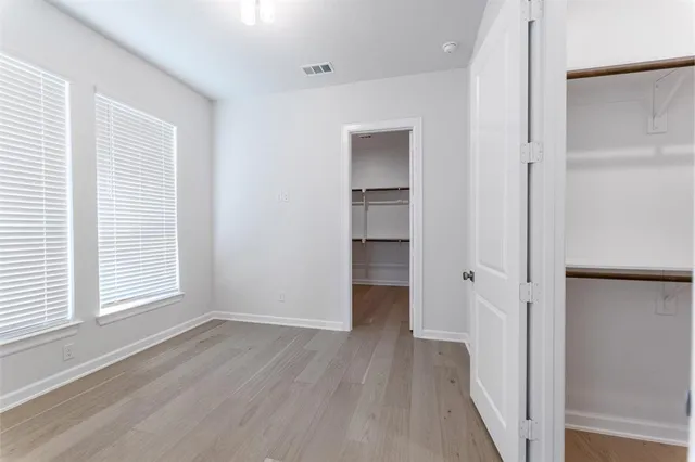 an empty room with wooden floor closet and windows