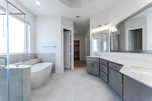 a spacious bathroom with a double vanity sink large mirror and a bathtub