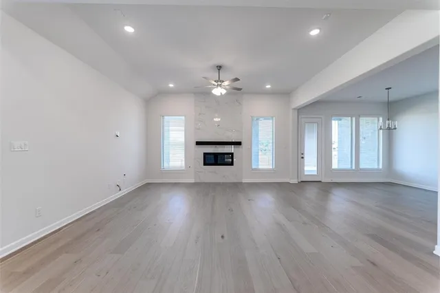 an empty room with wooden floor fireplace and windows